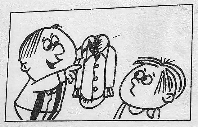 A boy points to a shirt he is holding.